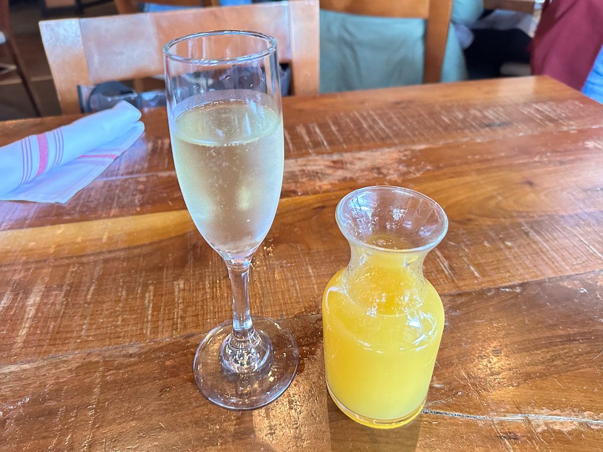 water in a champagne glass and a small pitcher of orange juice